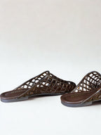 Pair of brown sandals with woven design on a white background