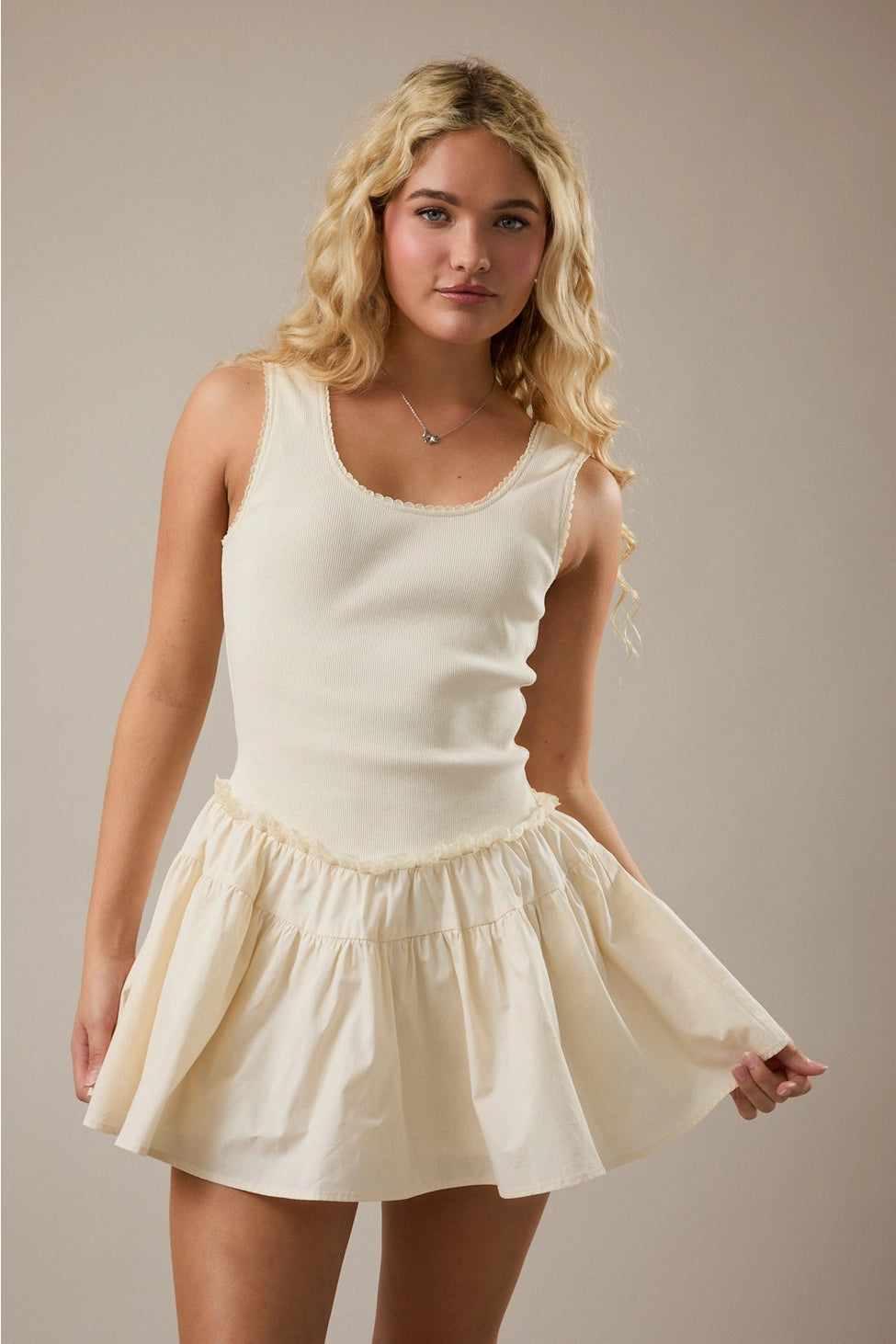 Woman wearing a cream-colored sleeveless top and skirt against a neutral background