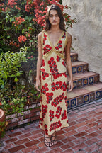Woman in a floral dress standing on a stone staircase with plants in the background