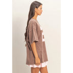 Woman wearing a brown oversized t-shirt with a white undershirt underneath on a plain background