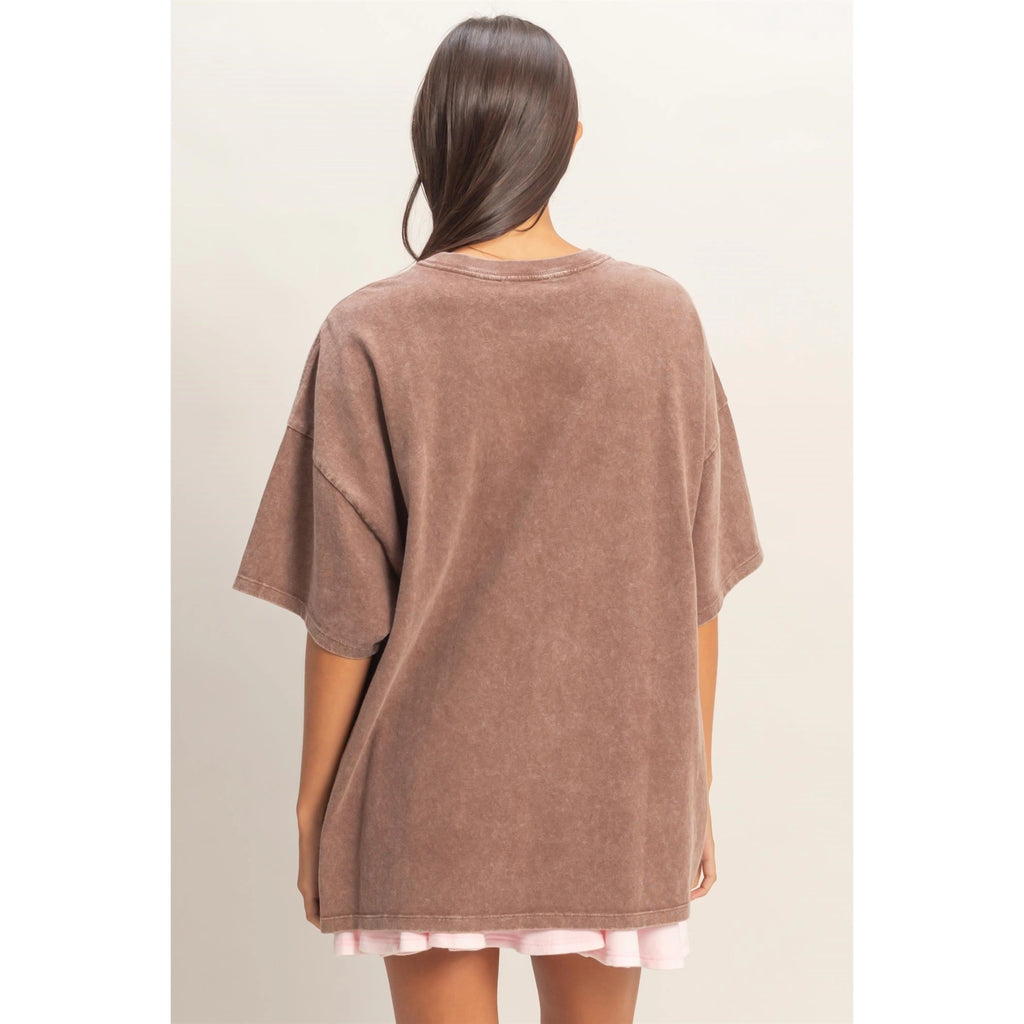 Person wearing a brown oversized t-shirt on a plain background