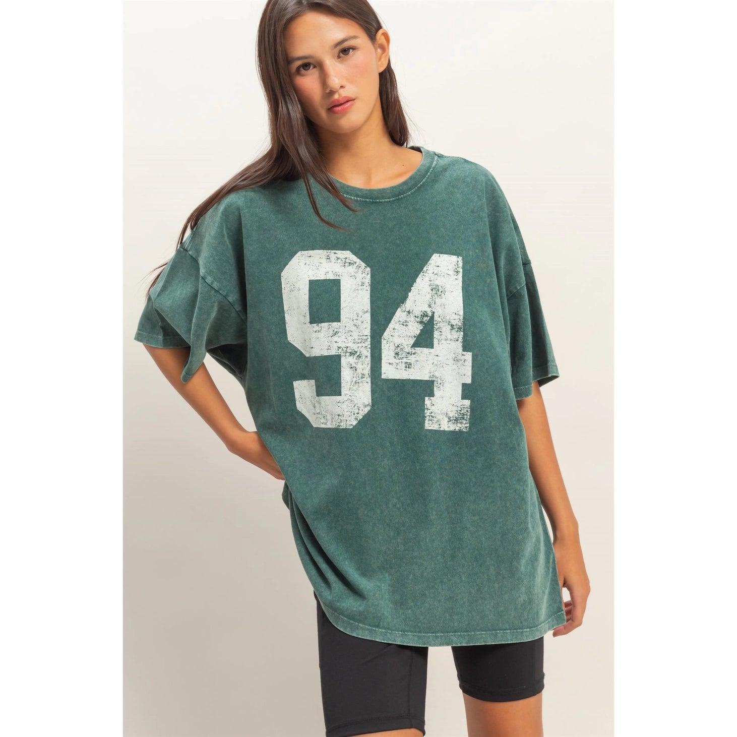 Woman wearing a green t-shirt with the number 94 on a plain background