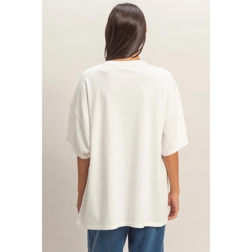 Person wearing a white oversized t-shirt and blue pants on a plain background