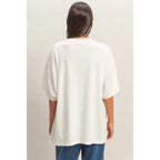 Person wearing a white oversized t-shirt and blue pants on a plain background